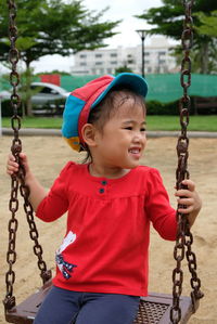 Cute girl looking away while sitting on swing in playground