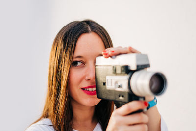 Close-up of woman looking away while holding camera 