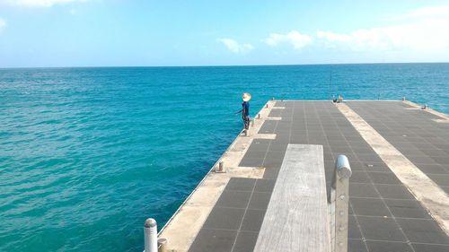 Man fishing on pier in sea against sky