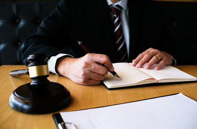 Cropped image of judge writing in book at desk
