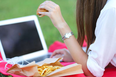 Midsection of woman holding smart phone on table