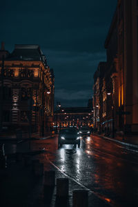 Dark evening street after rain with moving cars on the road