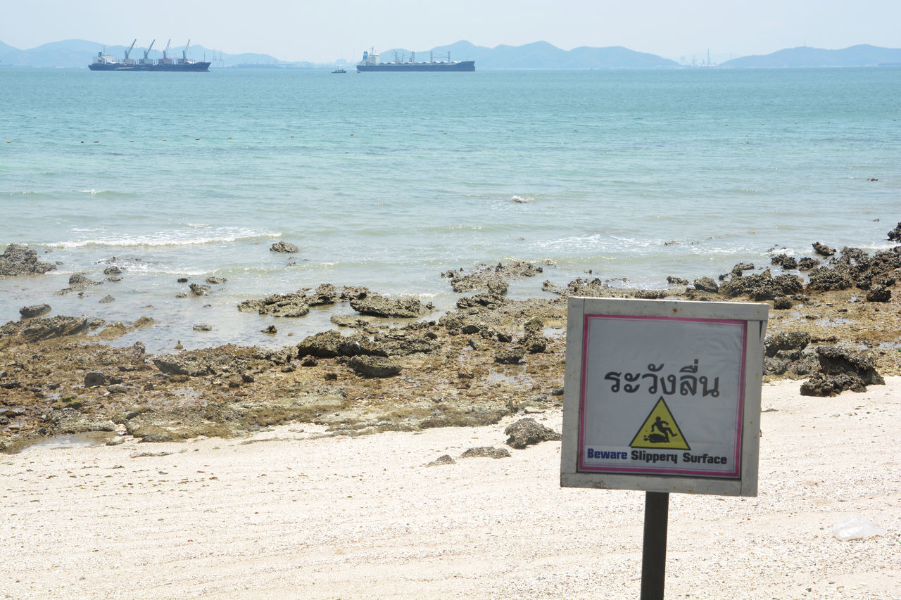 INFORMATION SIGN ON BEACH AGAINST SEA