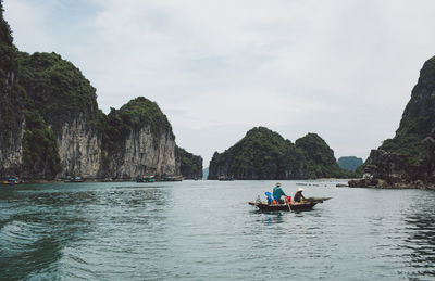 People on boat at halong bay by mountains