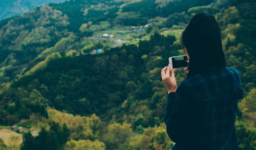 Woman photographing lush landscape