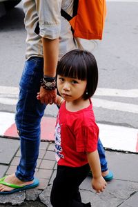 Portrait of girl walking with mother on footpath