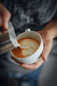 Cropped hand making coffee at cafe