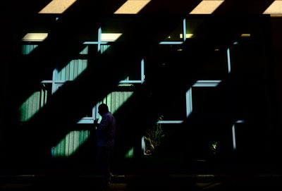 Silhouette man standing in illuminated dark room