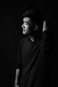 Young man looking away against black background