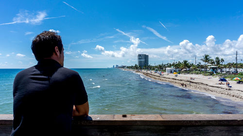 Rear view of man looking at sea against sky