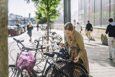 Businesswoman listening music while standing near bicycle at parking station