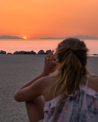 Rear view of woman looking at sea during sunset