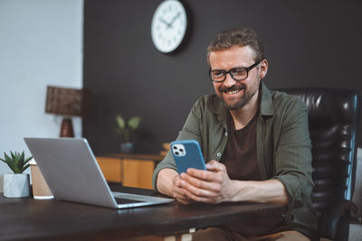 Young man using mobile phone while sitting on sofa at home