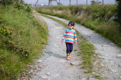 Rear view of boy walking on footpath