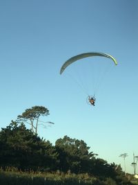 Low angle view of person paragliding against clear sky
