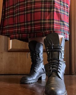 Low section of woman standing on hardwood floor with scotish pattern and boots 