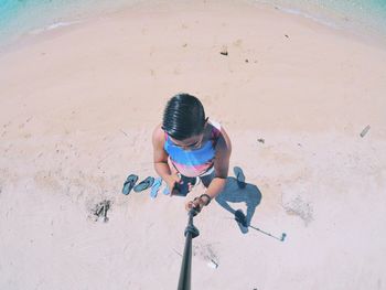 High angle view of young man taking selfie while using mobile phone at beach