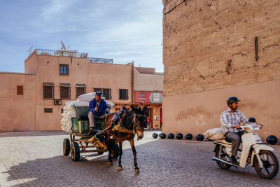 People riding horse cart in city