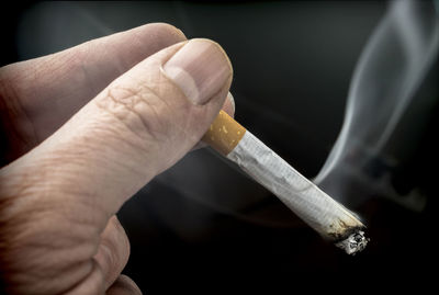 Close-up of hand holding cigarette