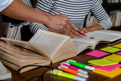 Midsection of man reading book on table