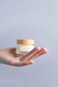 Cropped hand of person holding pills against white background