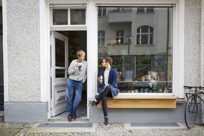 Male and female colleagues having coffee at entrance of art studio