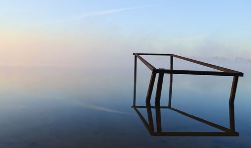 Metallic structure by sea against sky