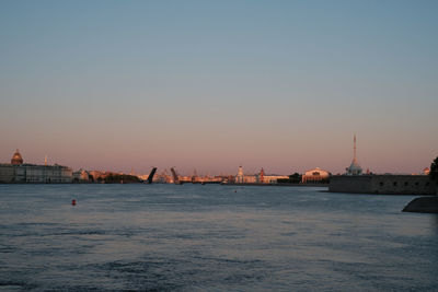 Scenic view of river by buildings against sky during sunset