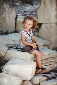 Portrait of a smiling girl sitting on rock