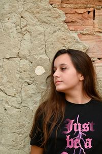 Young woman looking away against wall