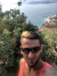 Portrait of young man with sunglasses against trees