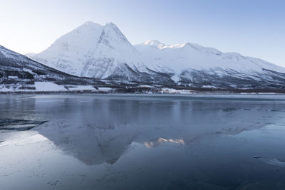 Scenic view of lake by snowcapped mountains against sky