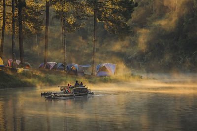 People on boat in river against trees in forest