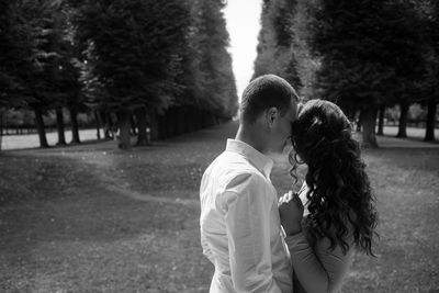 Couple romancing while standing on grassy field at park