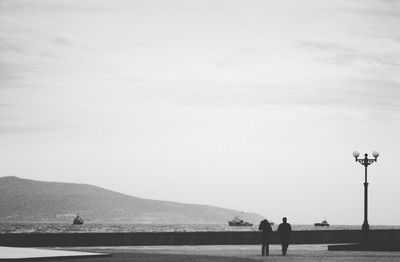 People standing on street by mountain against sky