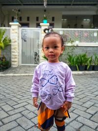 Portrait of cute girl standing on footpath