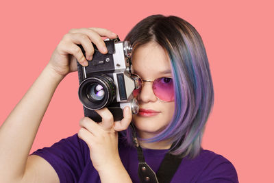 Close-up of woman holding camera against blue background