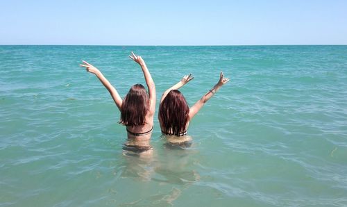 Rear view of young woman in sea against clear sky