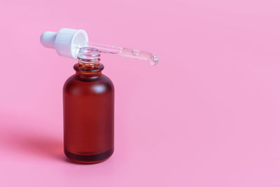 Close-up of glass bottle against pink background