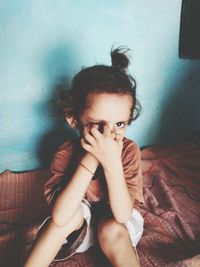 Young woman sitting on bed at home