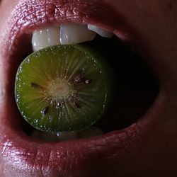 Close-up of woman eating kiwi