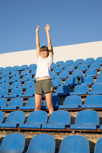 Full length of woman jumping against clear blue sky