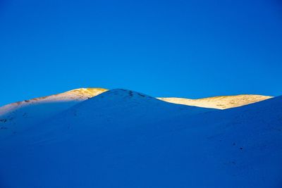 Scenic view of snowcapped mountains against clear blue sky