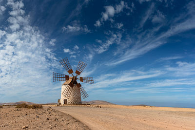 Traditional stone windmill on field against beautiful sky