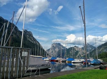 Boats moored at harbor against sky