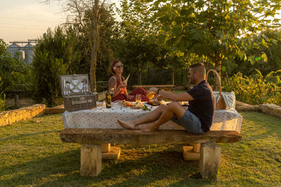 Couple sitting on table by tree