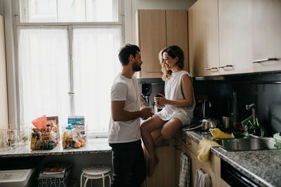 Friends standing in kitchen at home