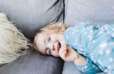 High angle portrait of girl lying on sofa at home