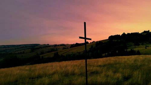 Scenic view of grassy field against sky at sunset