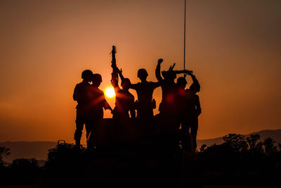 Silhouette people standing against sky during sunset